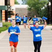 Individuals nearing finish line holding up their hands celebrating